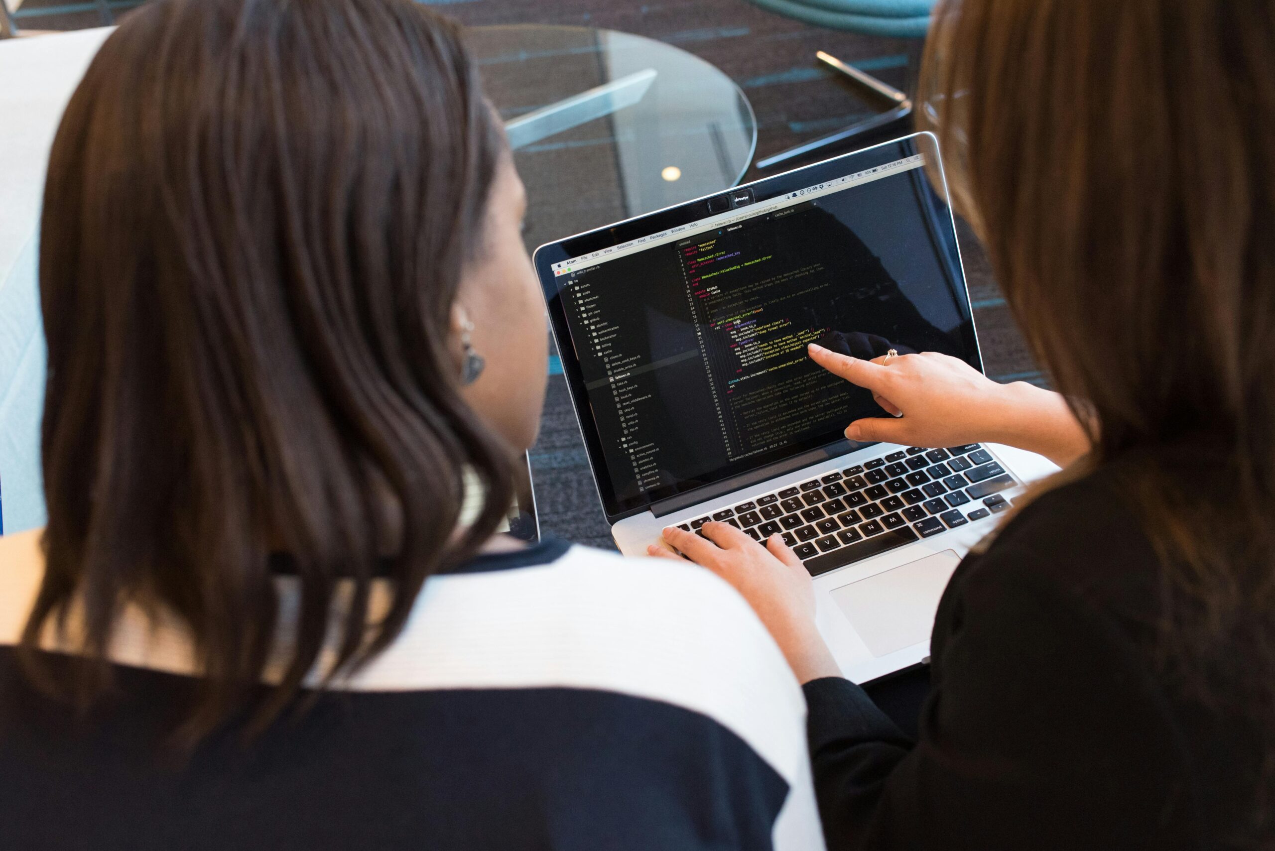 Web Development in 2026: A Complete Guide for Businesses and Beginners Two women working together on software programming indoors, focusing on code.