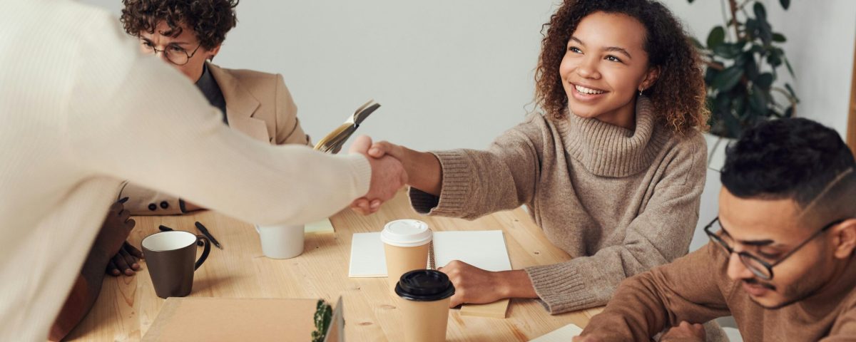 Colleagues in a positive meeting, exchanging a handshake while discussing projects.